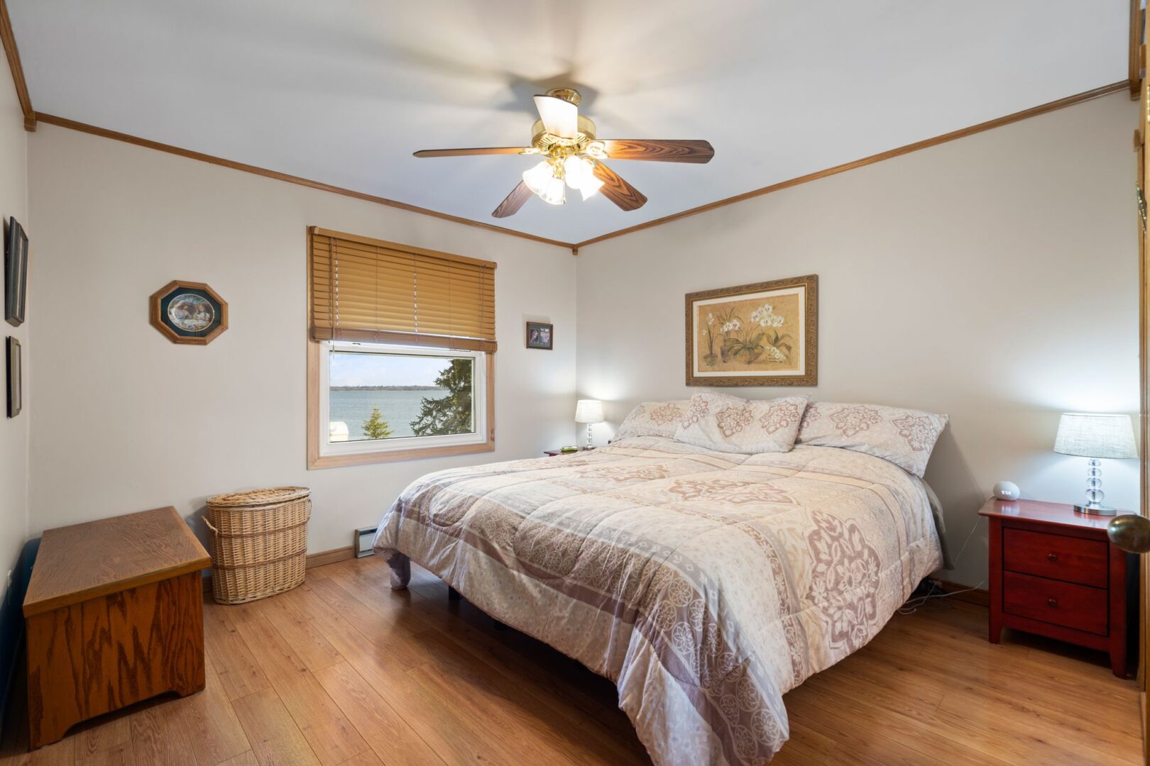 A primary bedroom with a big bed, a ceiling fan, and hardwood flooring.
