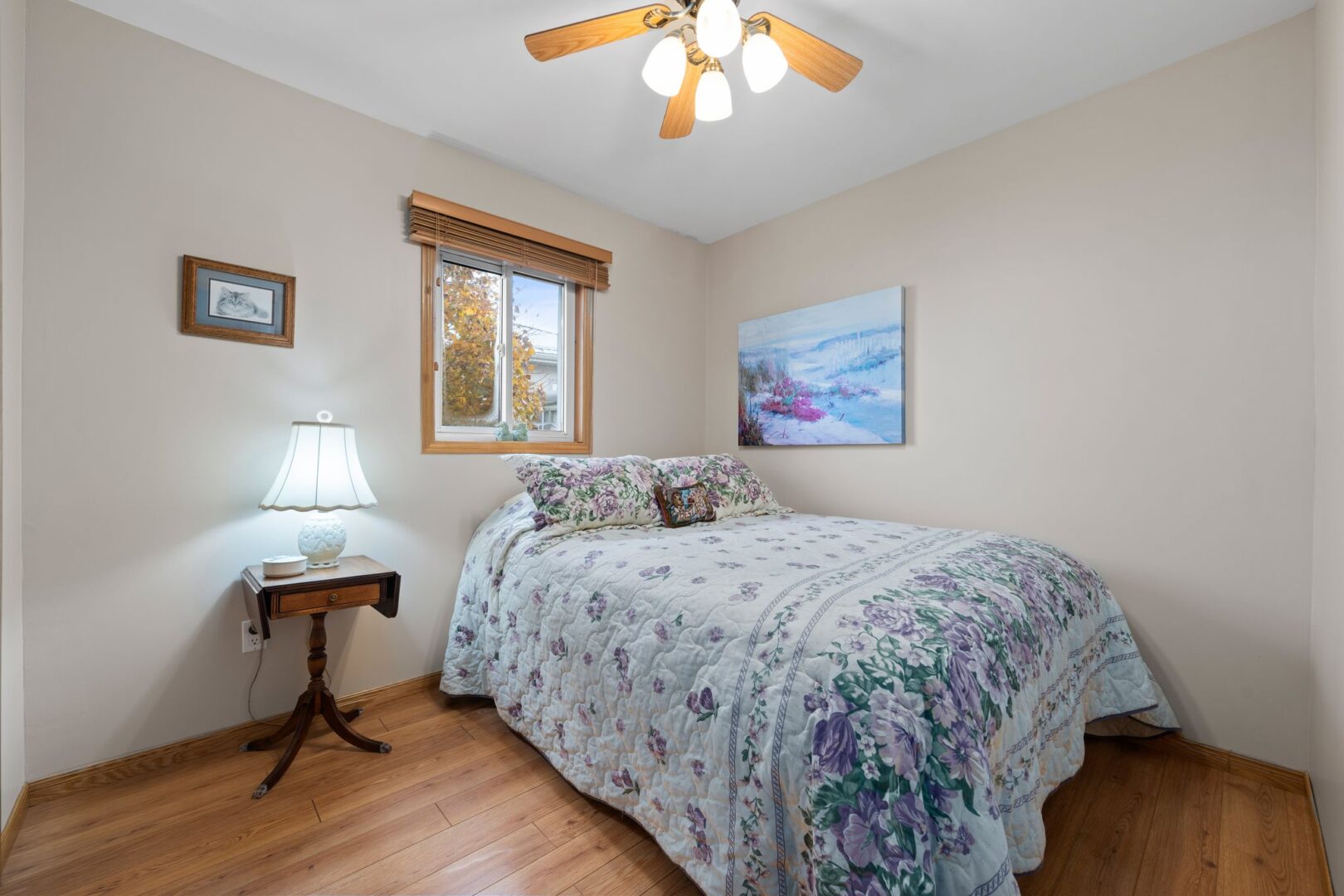 A small bedroom with a double bed, hardwood flooring, and a ceiling fan.