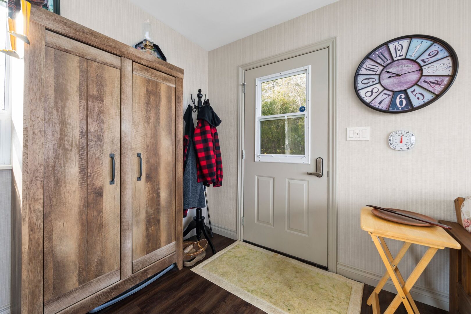 Inside the front entrance of a bunkie with wood flooring, a wardrobe, and a coat rack.