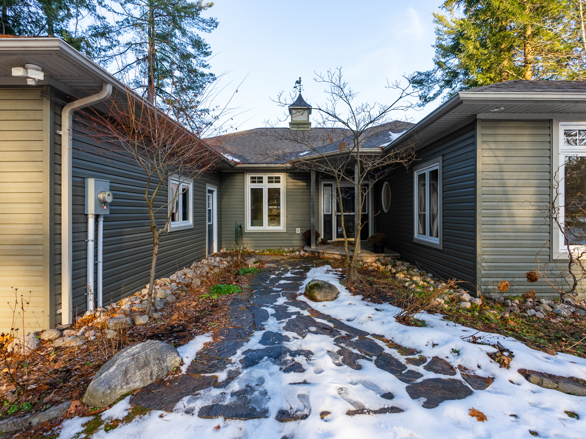 A snow-covered walkway leads through the middle of a U-shaped house to the front door, like a little front courtyard.