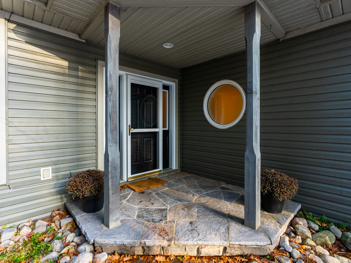 A front door with a small covered patio leads into a home.