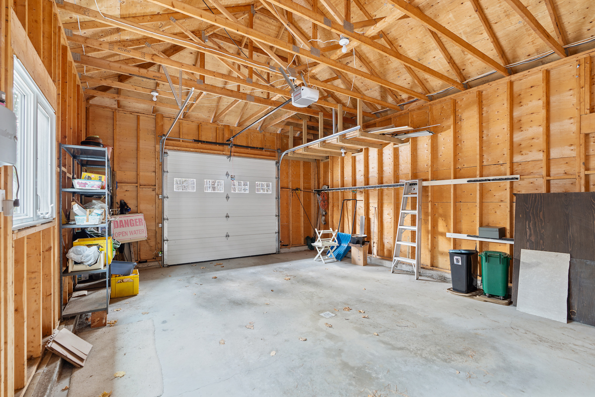 A one-car garage with exposed beams and some storage shelves.