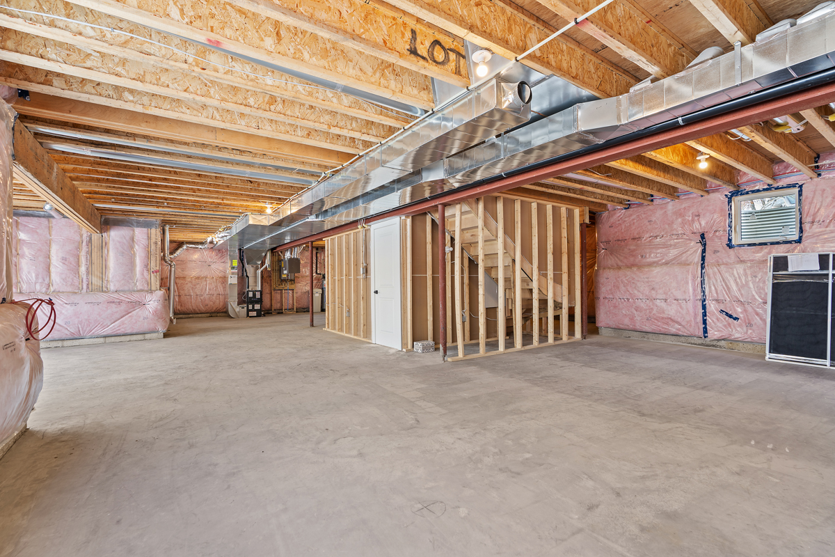 A large unfinished basement area with exposed wooden beams and insulation.