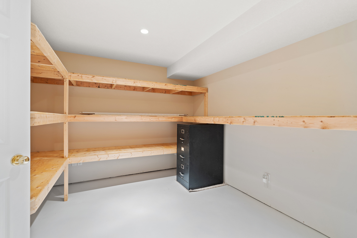 A big storage closet with wooden shelves lining the walls.