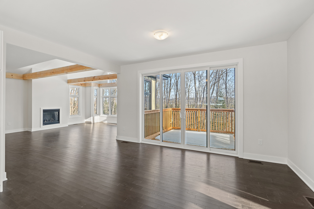 A bright area with dark hardwood floors, white walls and a white ceiling. Sliding glass doors open up into a sunroom ahead.