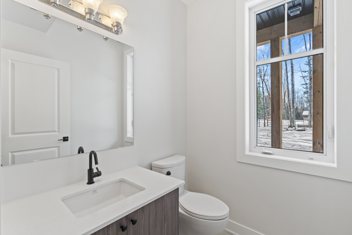 A small bathroom with a toilet, a sink, and a window.