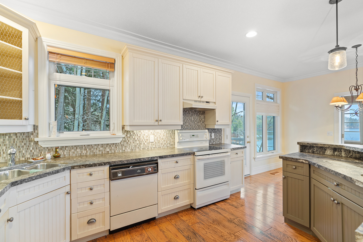 A big, bright kitchen area with lots of countertop space, hardwood floors, and older appliances.