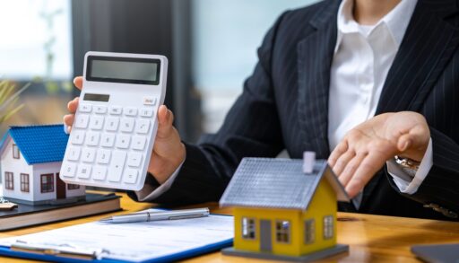 woman holding a calculator beside a miniature house to indicate the appraisal value