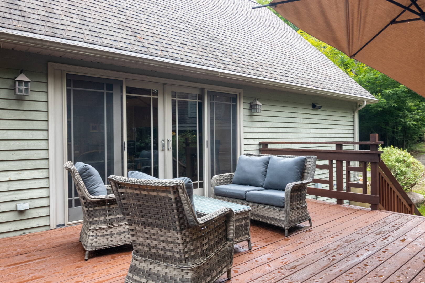 A deck with outdoor seating extends off the side of a cottage.