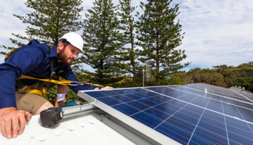 Solar panel technician with drill installing solar panels on roof
