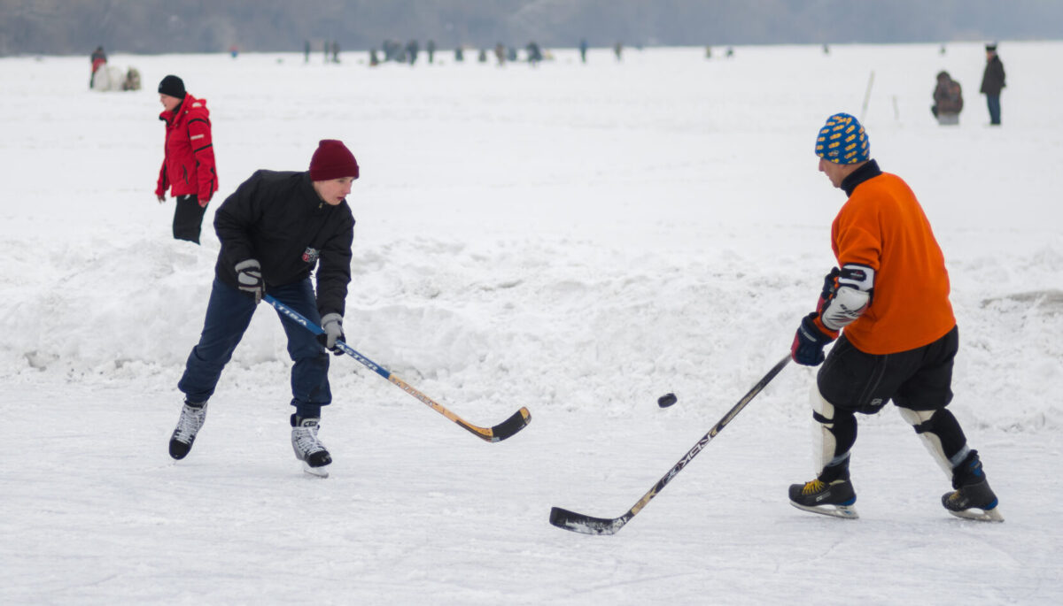 two people play hockey on outdoor ice