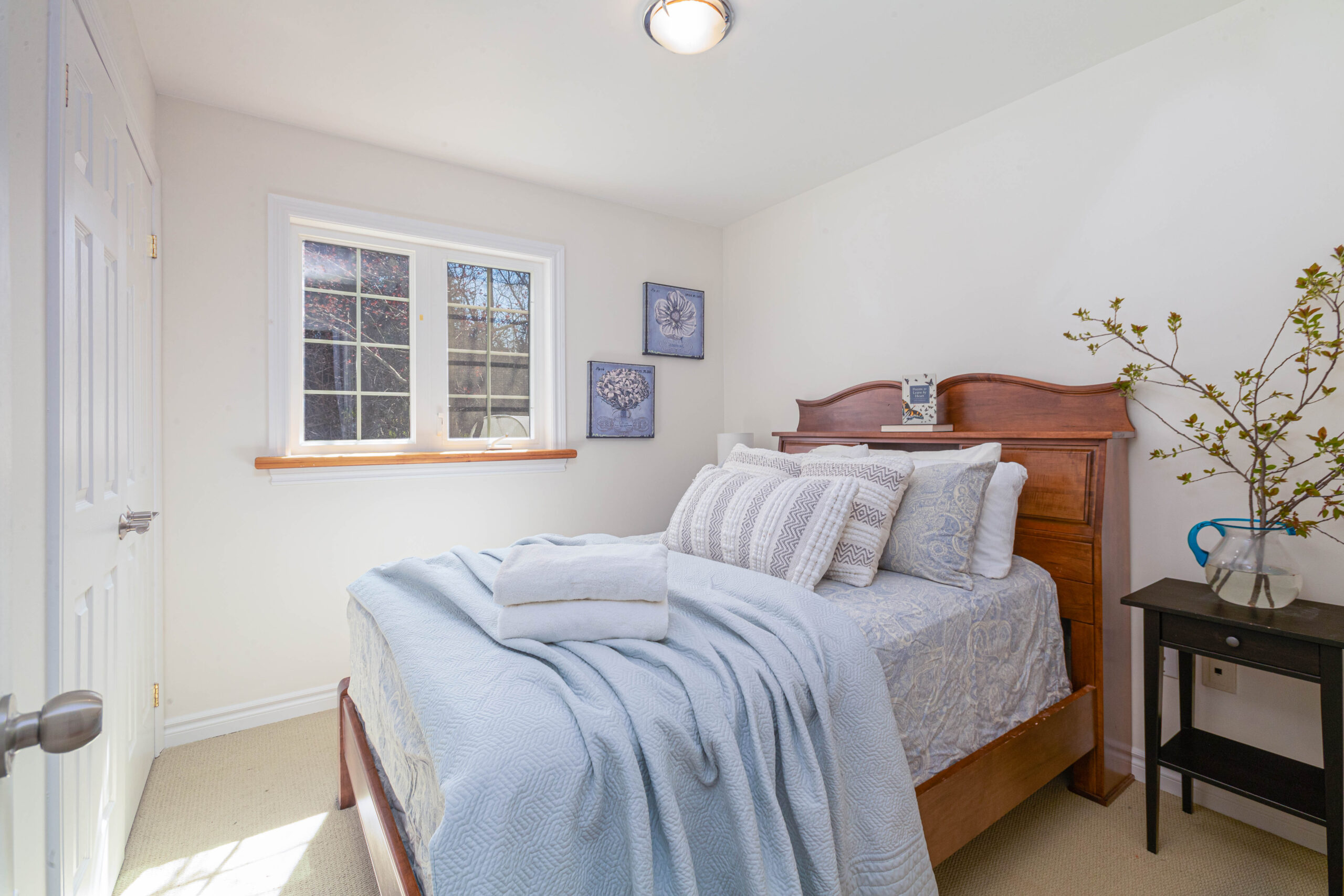 A bright bedroom with a big bed, cream walls, and a small window.