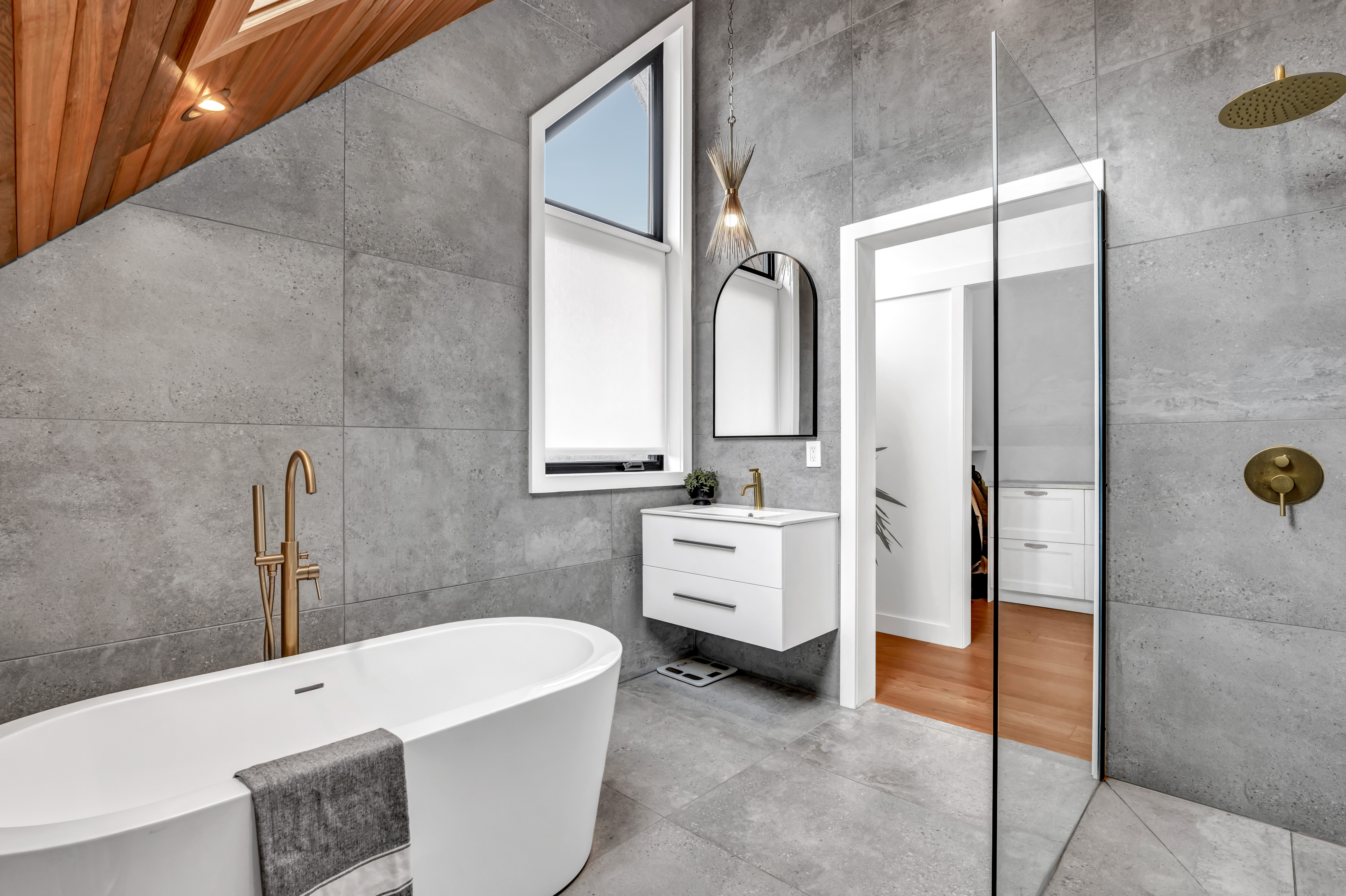 A bright, modern bathroom with a walk-in shower, a soaker tub, a sink, and a wood-panelled ceiling.