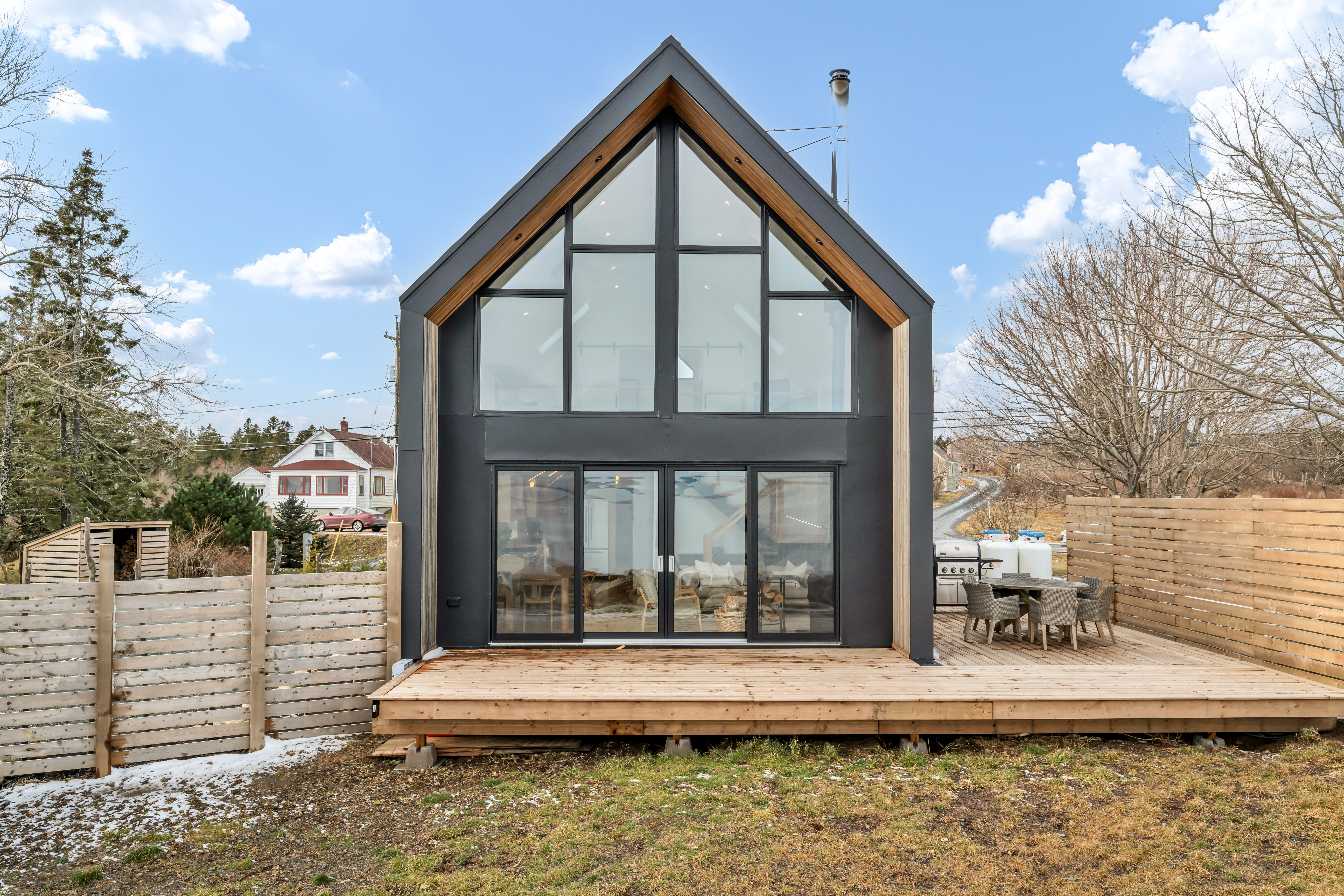 A modern, two-story oceanfront home with a wrap-around deck and floor-to-ceiling windows.