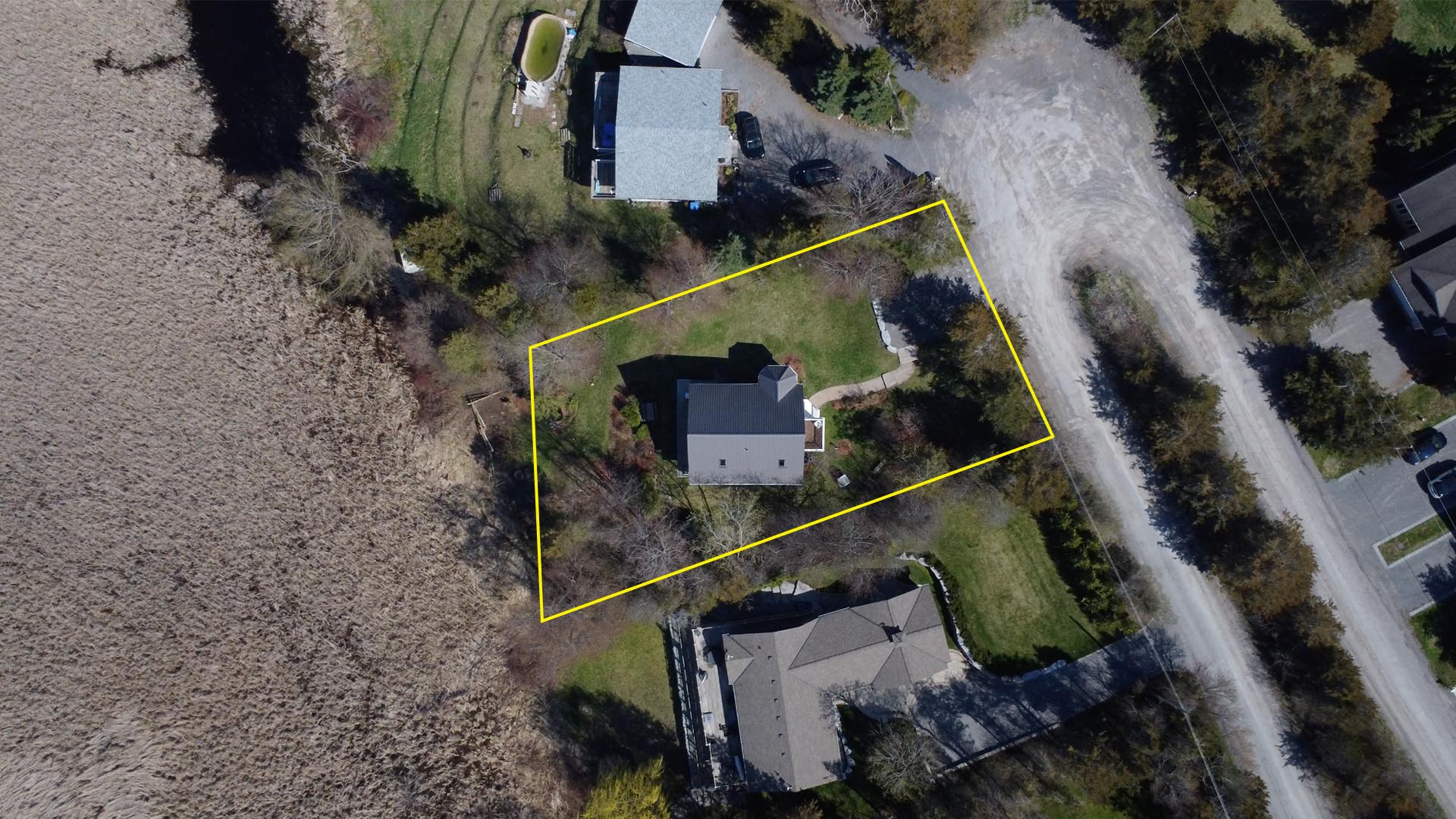 Aerial view of three homes in a rural area. A yellow rectangle around the home in the middle indicates the property area.