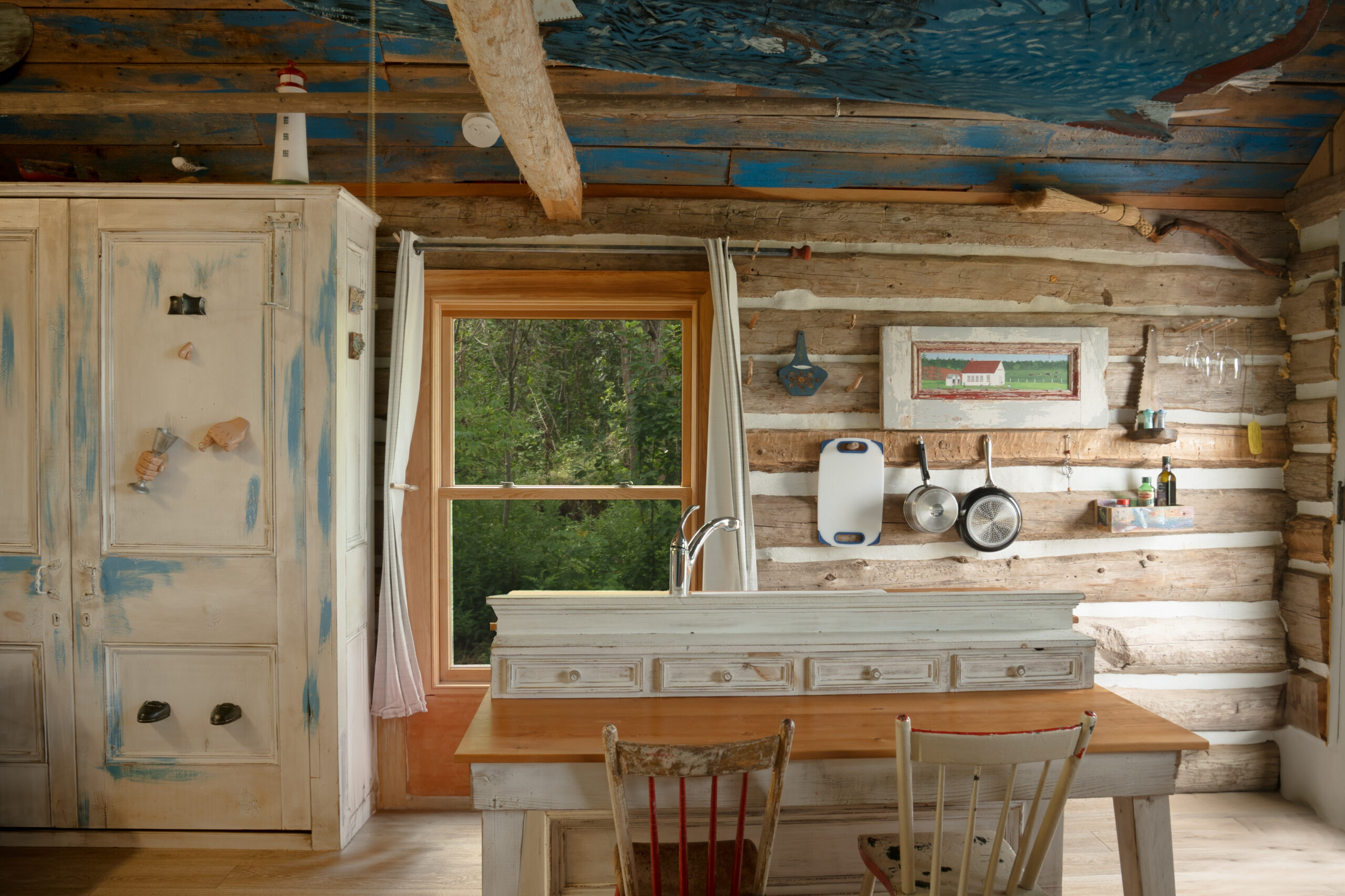 Interior of a small log cabin, with a small table and a sink.