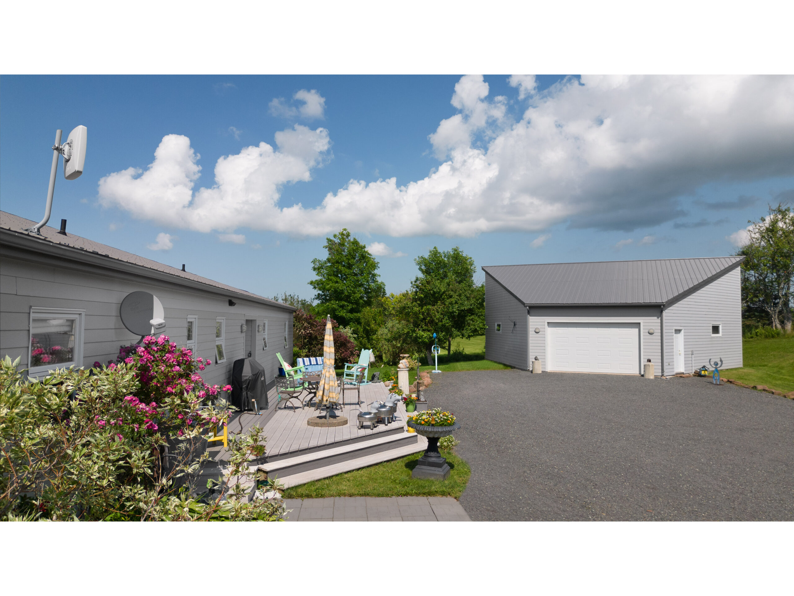 A big home with a large front porch and a big driveway. Adjacent to the home is a large detached garage.