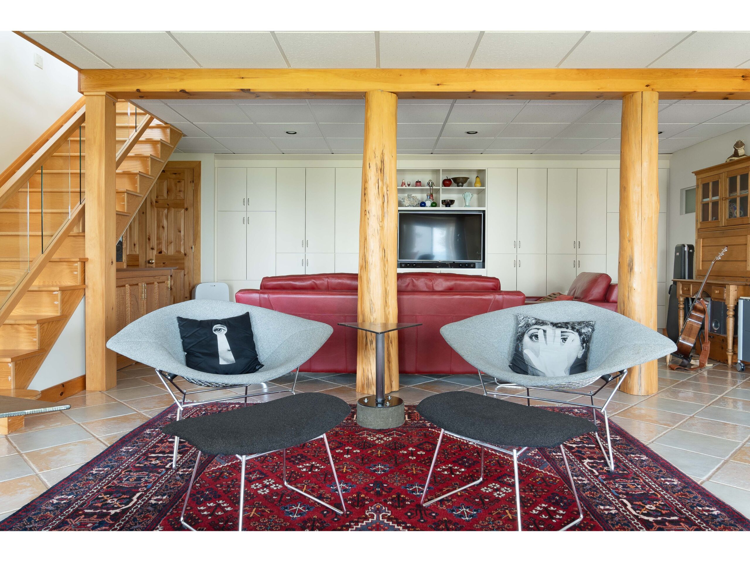 Two chairs sit on a red rug in a bright room.