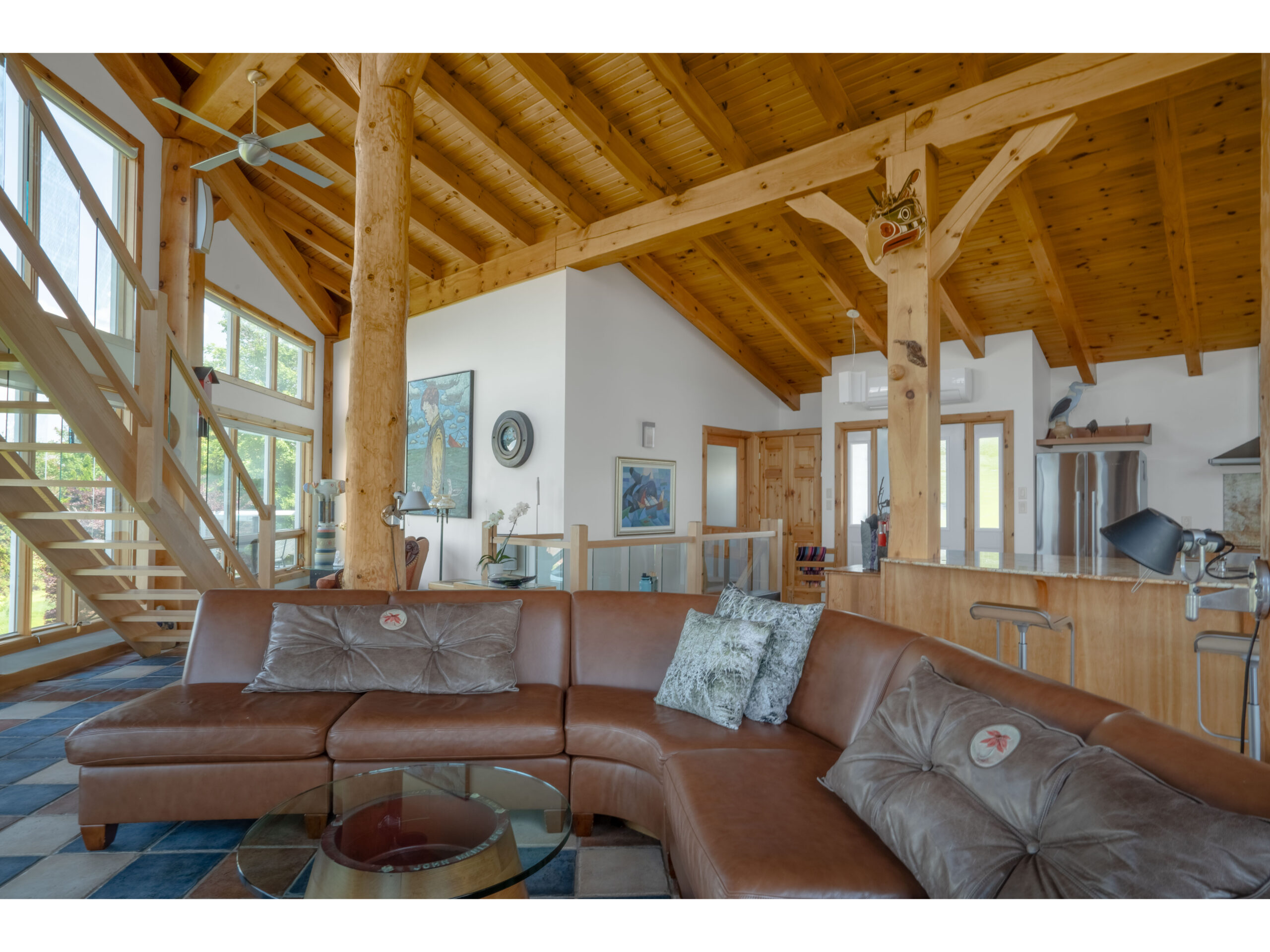 A large, bright, open-concept living area with colourful tiled flooring, wood accents, and a leather couch.