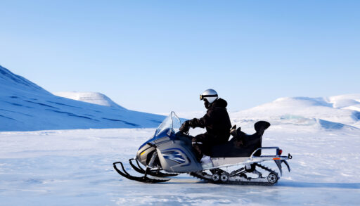 A snowmobile and rider travelling across a frozen lake