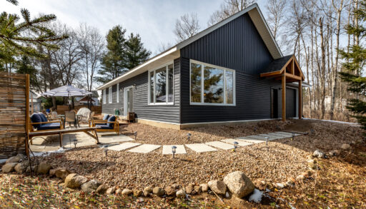 A blue-panelled house that sits on a large property with stepping stones that wrap around the hosue