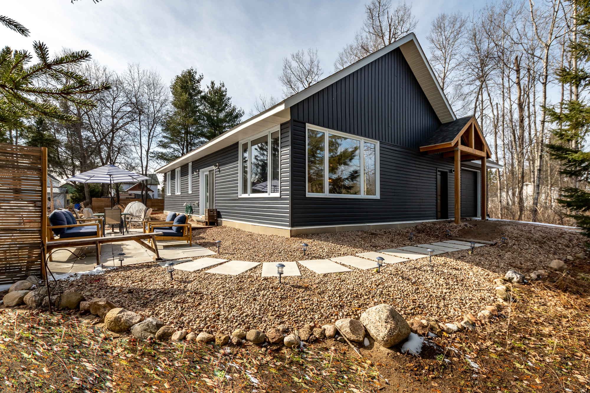 A blue-panelled house that sits on a large property with stepping stones that wrap around the hosue