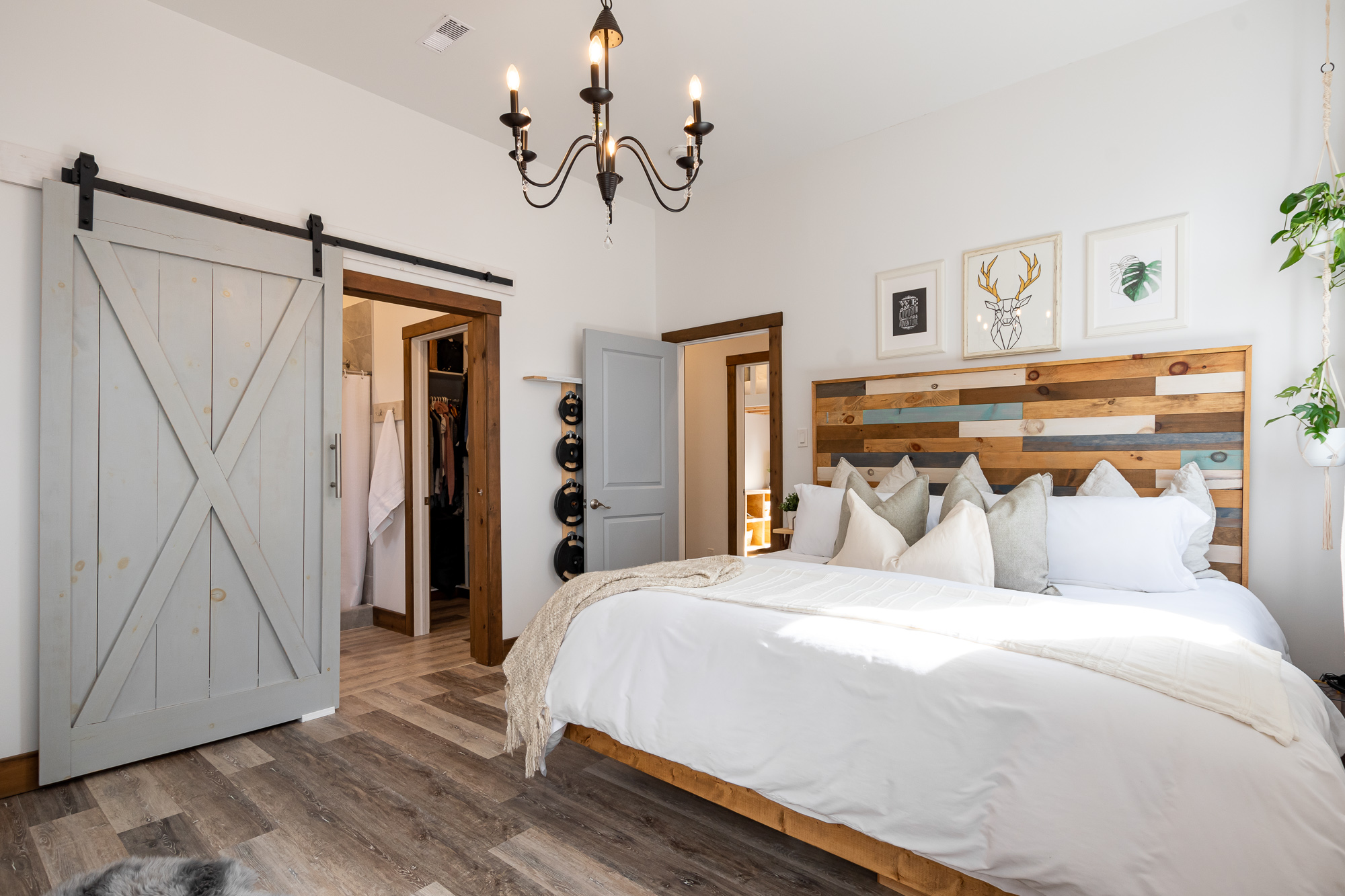 Large white bed is beside a grey sliding-barn door that leads to the bathroom