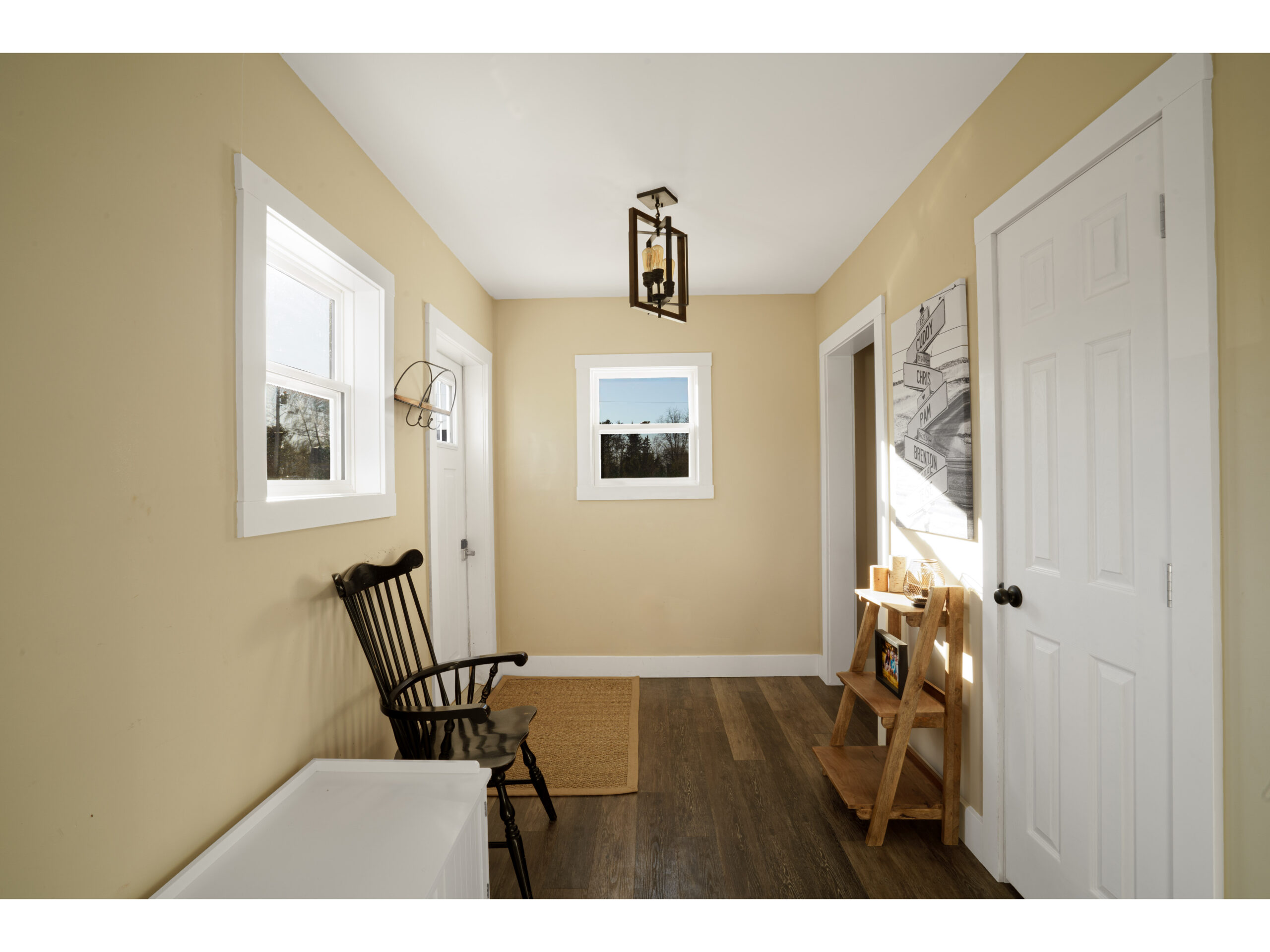 A small back entrance way with a chair, a short ladder shelf, and a door leading to outside.