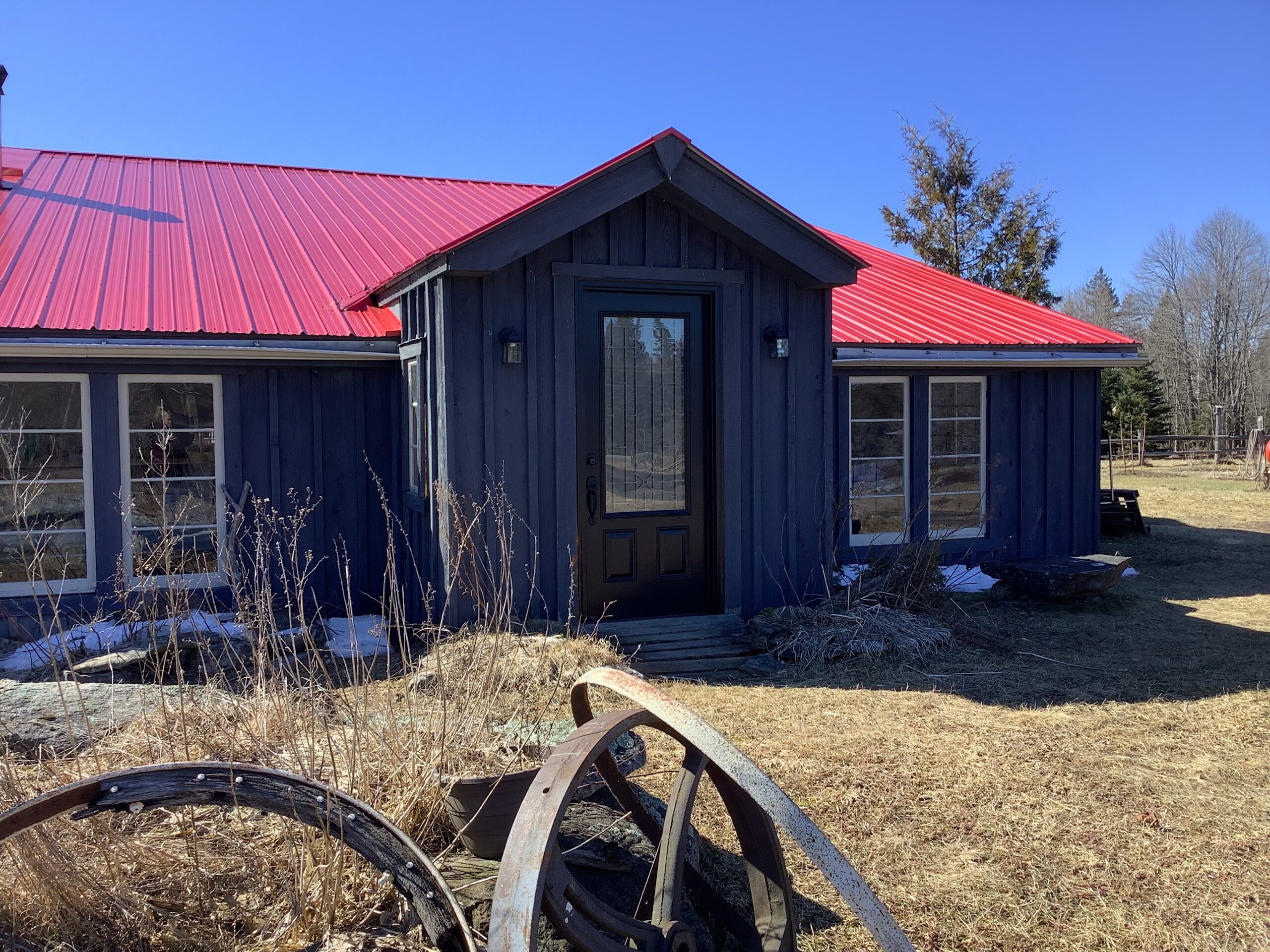 A small, modern guest house with a black exterior, big windows, and a red roof.