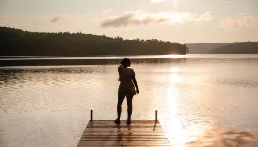 Carly stands at the end of a dock and looks out onto the lake.