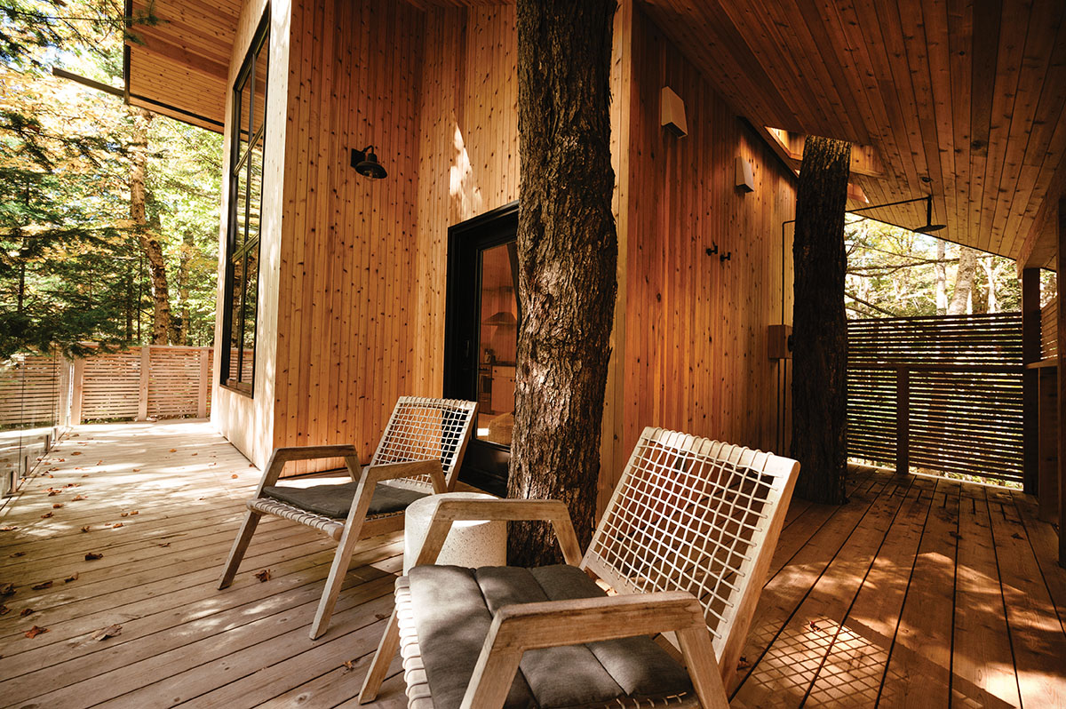 Two chairs and a side table are set up on the cottage's wraparound porch