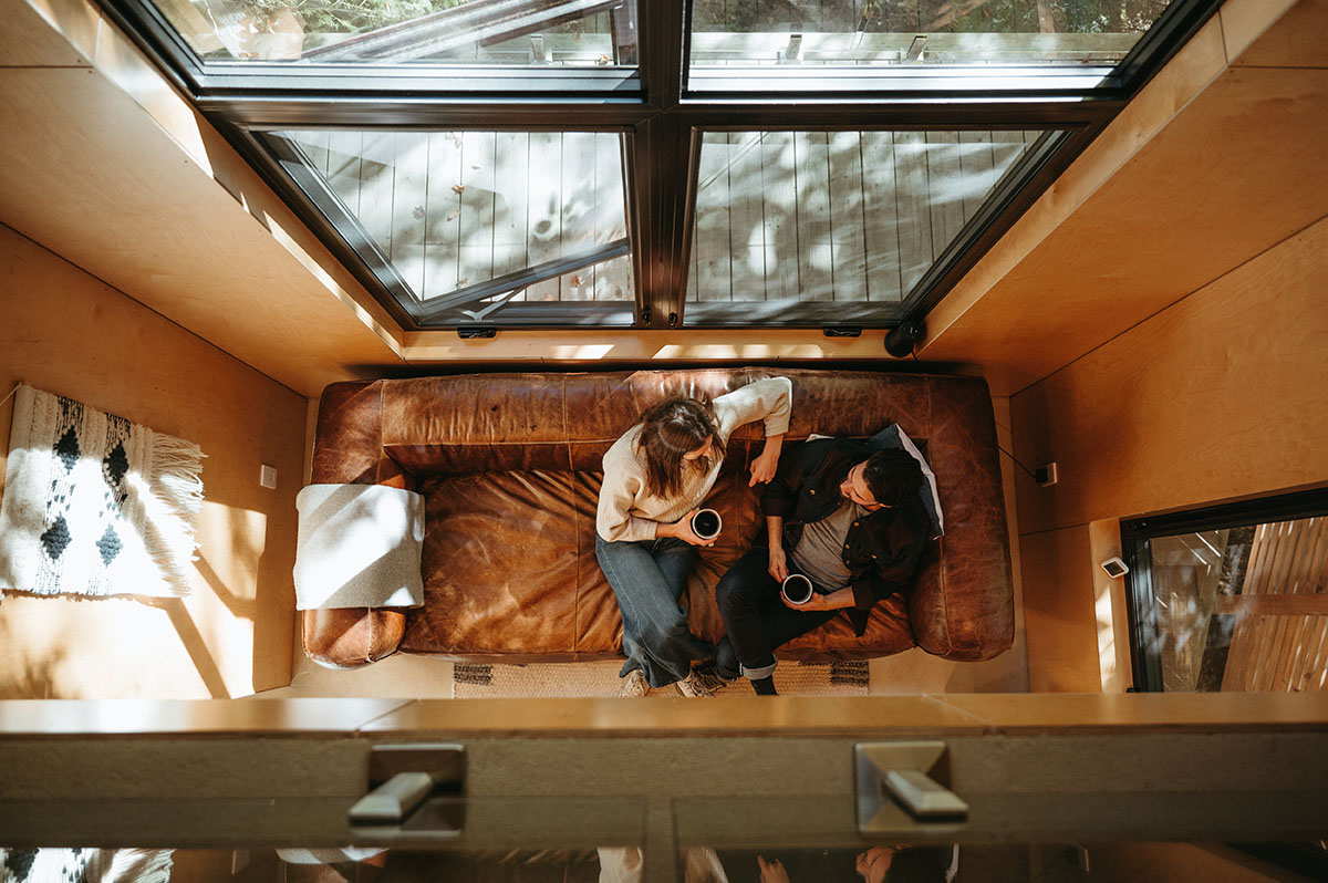 Overhead shot of Lauren and Cam sitting on their leather couch with mugs of coffee.