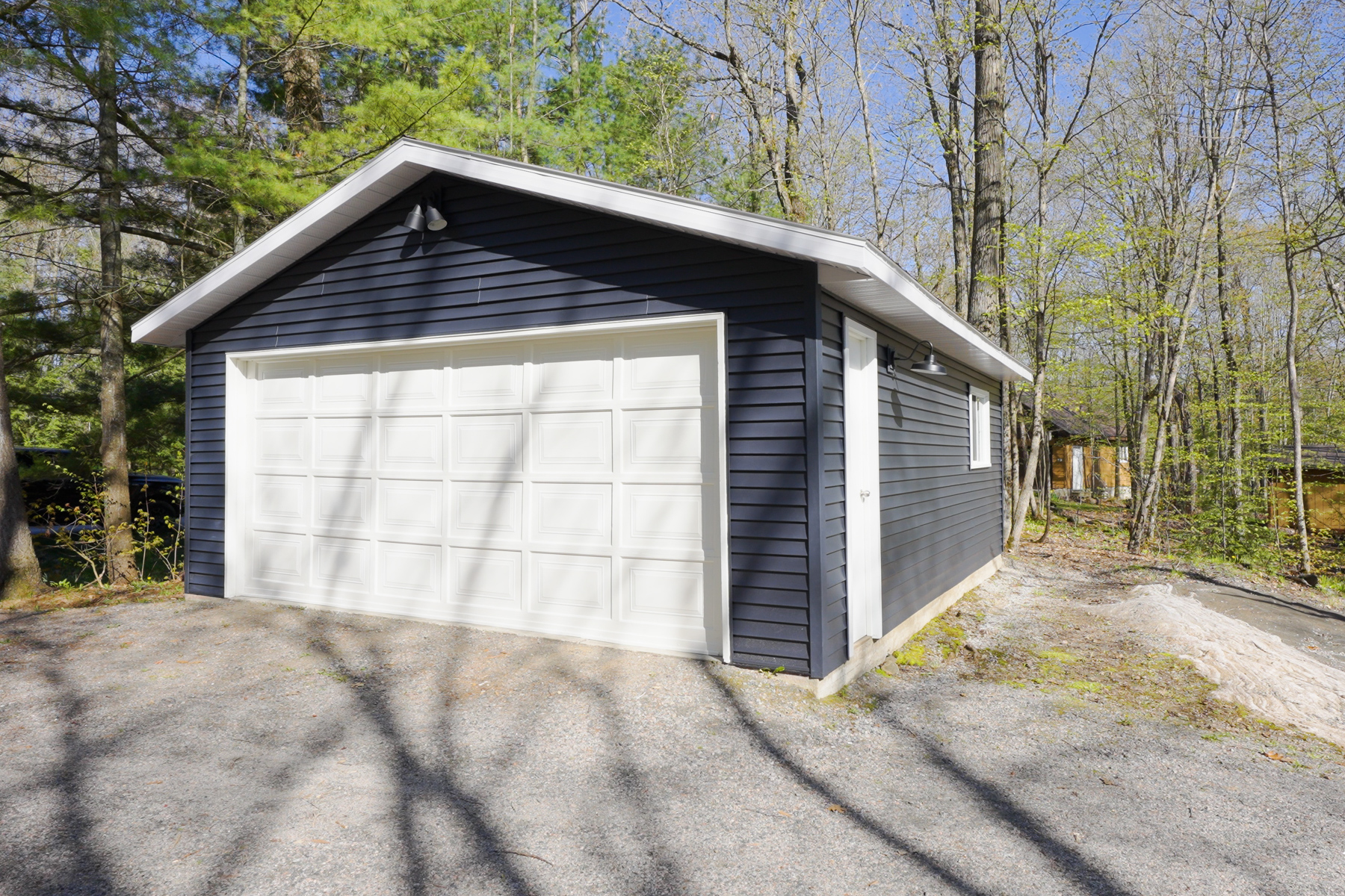 A detached two-car garage with navy blue exterior and a white door.