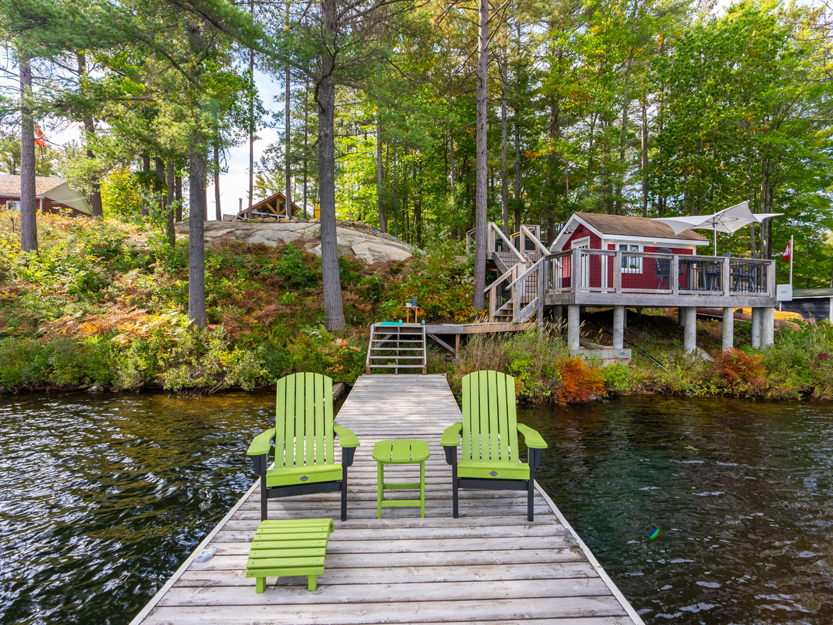 Green Muskoka chairs sit at the end of the dock. The dock leads up to the second deck