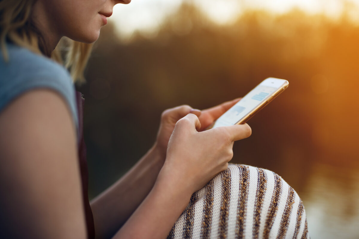 A woman texts on her smartphone outdoors