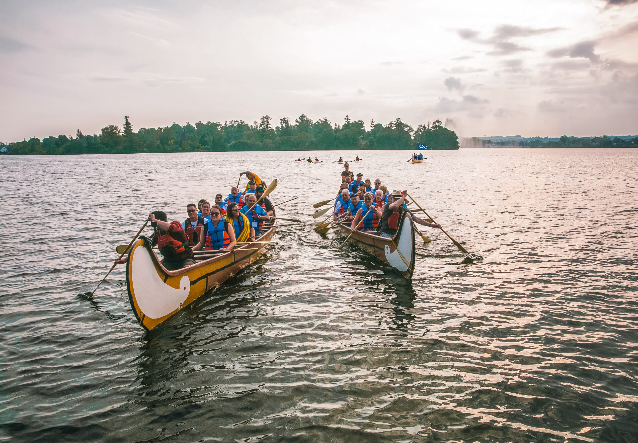 Groups of paddlers in two heritage canoes