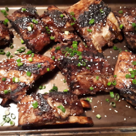 A baking sheet with ribs sprinkled with sesame seeds and green onion