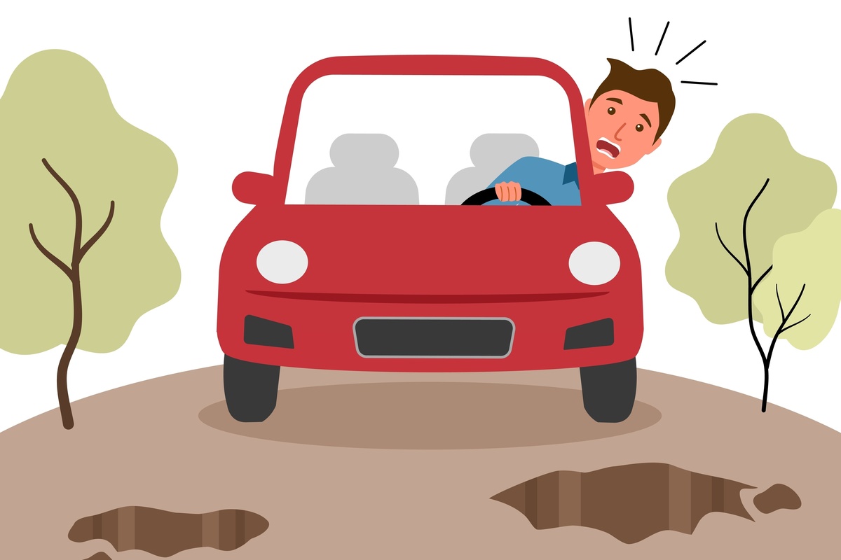 man driving a car over pot holes