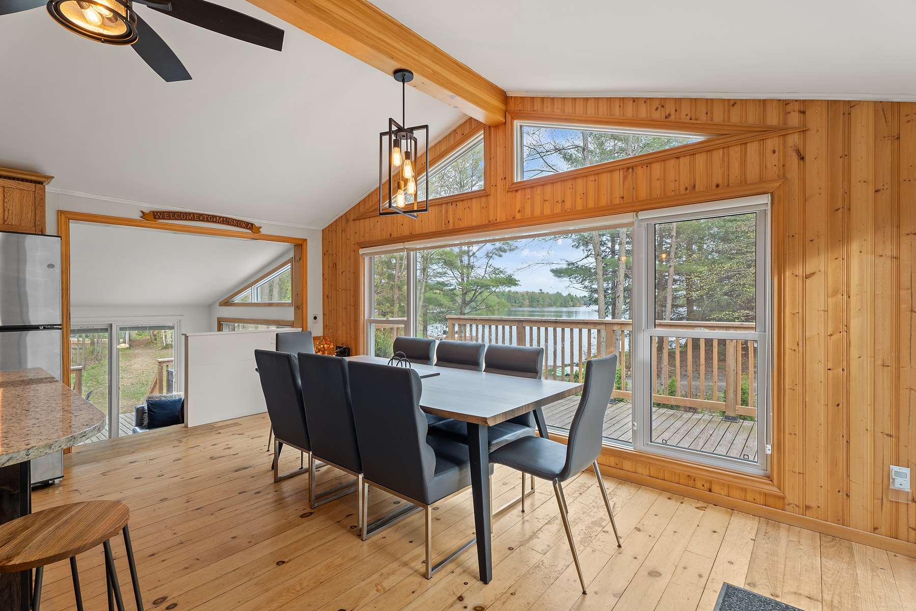 A dining table and chairs in front of a wall of big windows. Off to the side, steps lead down to another room.