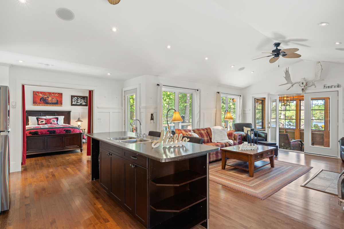 Brown kitchen island with brown marble countertop looks out to the primary bedroom to the left and main living area to the right
