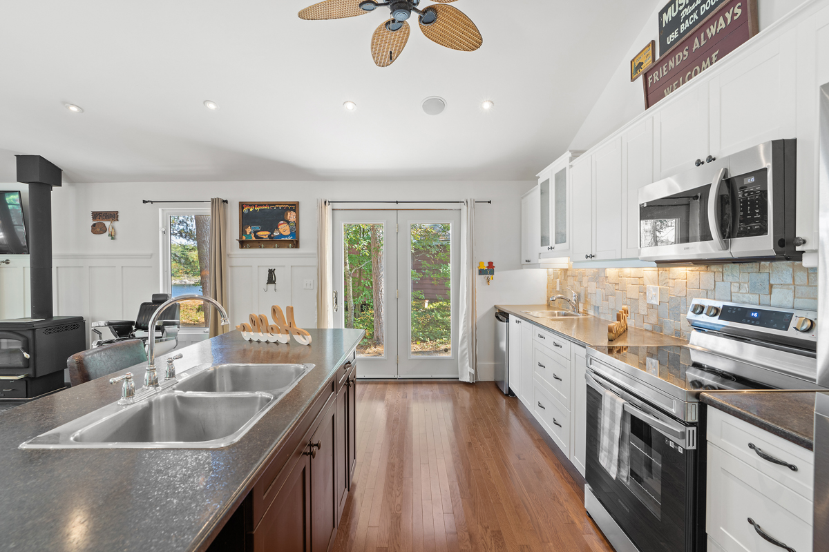 Side angle of kitchen features the kitchen island to the left and wall of stove, microwave, and counterspace to the right