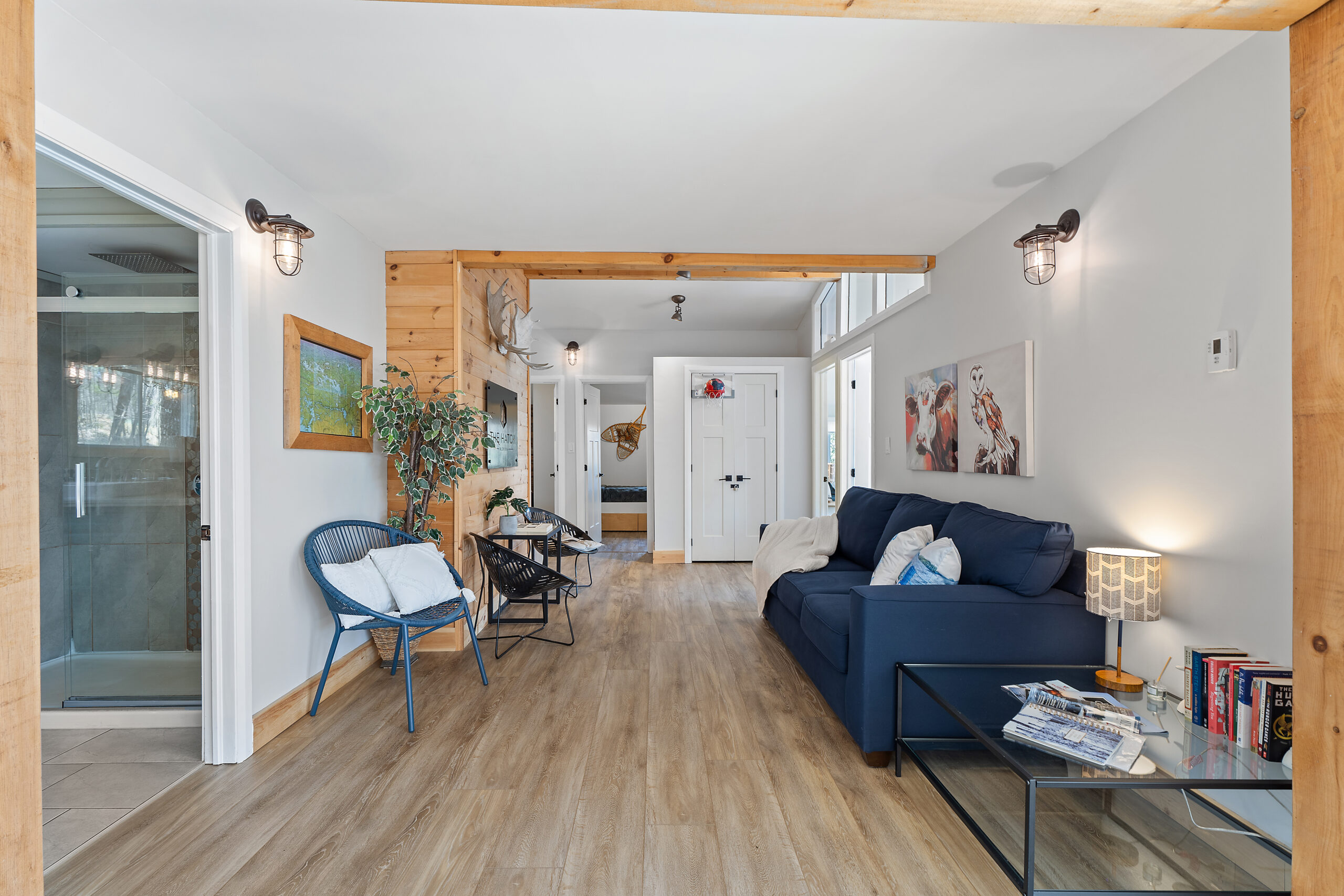 A wide hallway with a blue couch on the right and round chair on the left