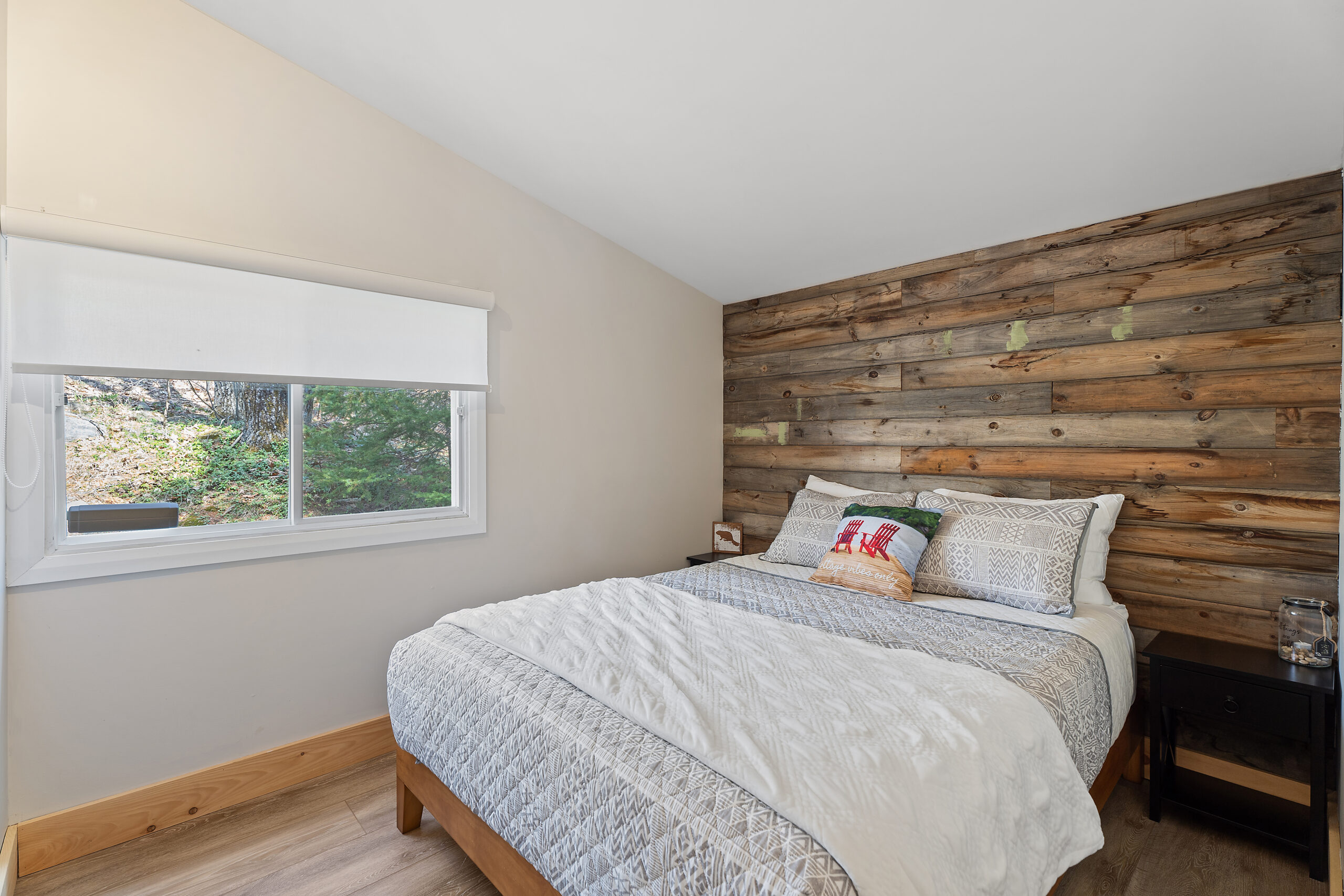 A quilted bed with a white blanket across the end has a panelled headboard