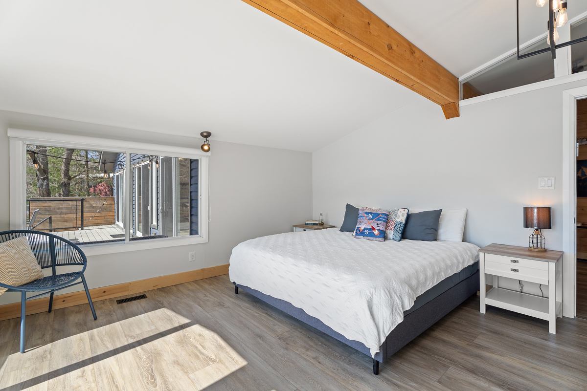 Reverse view of the white bed with a nightsrand next to it and windows to the left