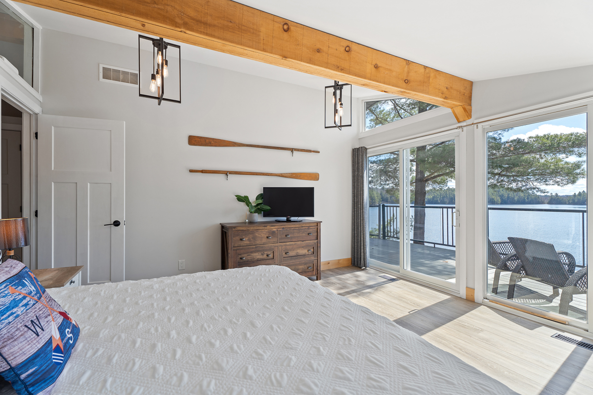 Reverse view of bed facing the deck, a TV on a table sits on an adjoining wall