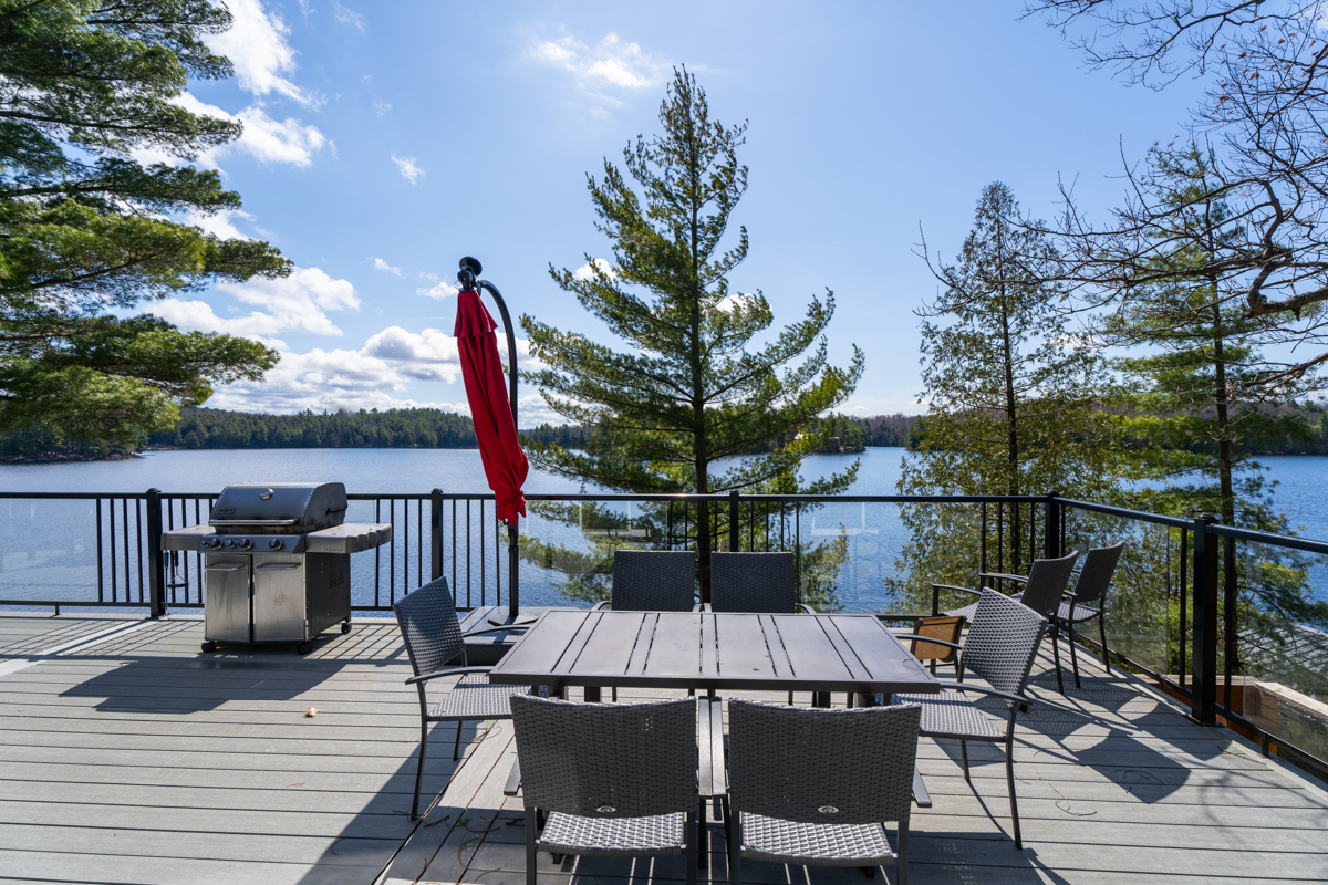 An outdoor dining area with closed red umbrella looks out onto the lake