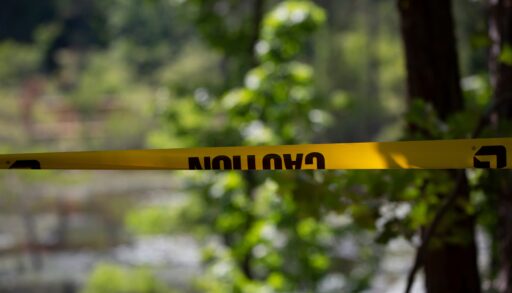 Close up caution tape blocking access to water and trees