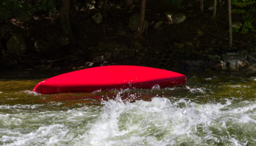Overturned canoe floats down in the river