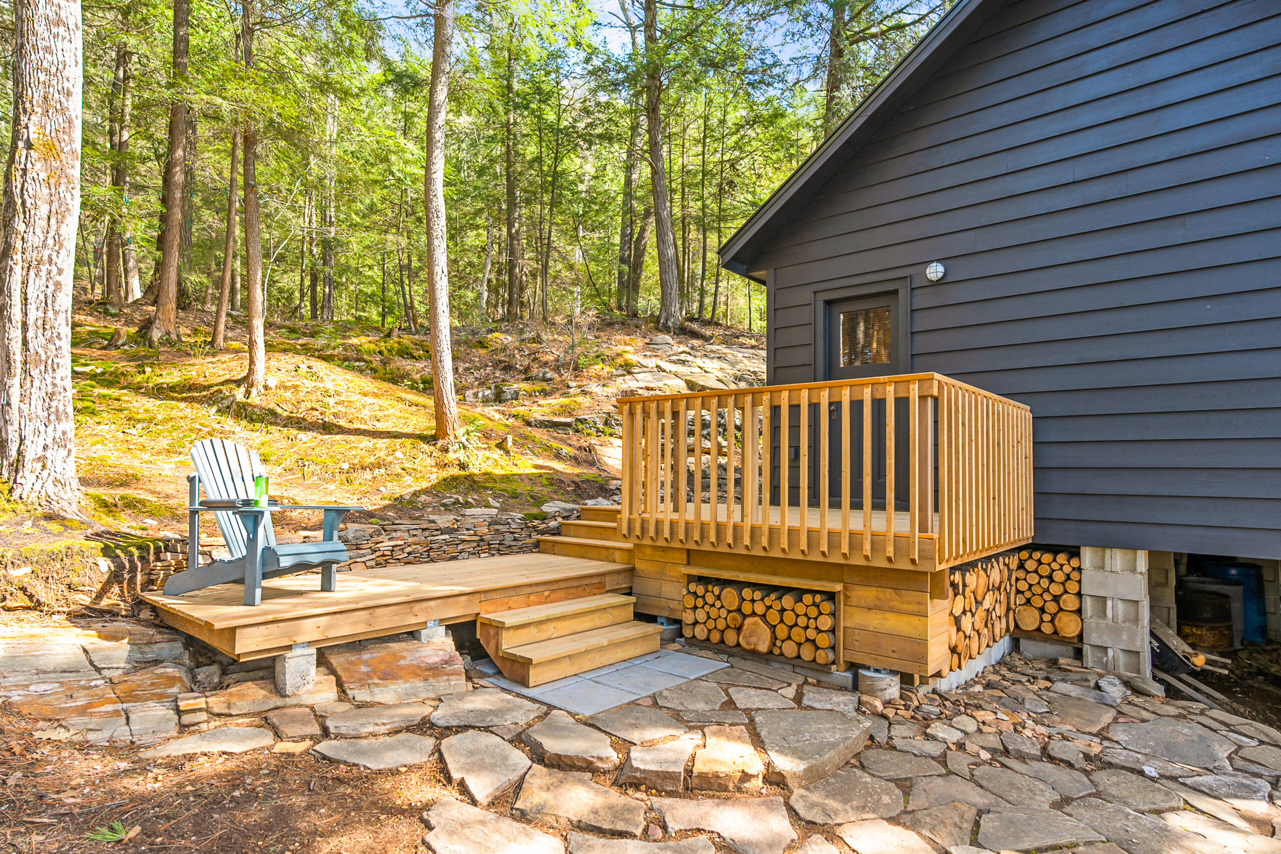 A small brown deck with a blue Muskoka chair attached to the cottage