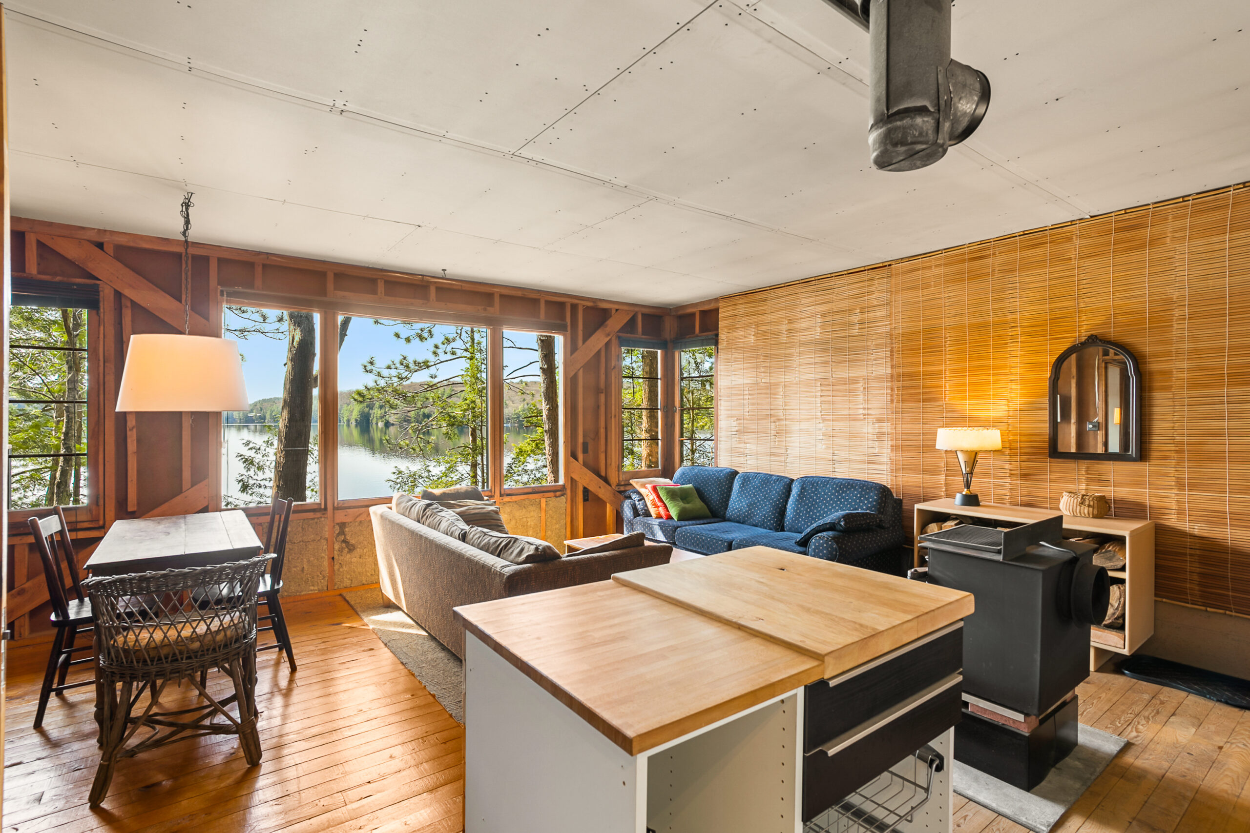 A small white kitchen island with a wood countertop in front of the living space with couches